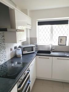 a kitchen with white cabinets and a microwave at One Bedroom Apartment hosted Be More Homely Serviced Accommodation & Apartments Birmingham With X1 King Beds Sleeps 4 in Birmingham
