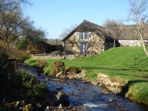 a stone house with a stream in front of it at Bearslake Inn in Bridestowe