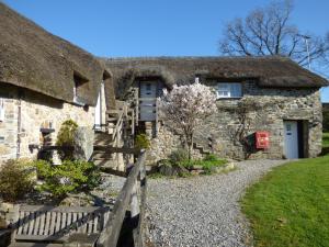 un ancien cottage en pierre avec un toit de chaume dans l'établissement Bearslake Inn, à Bridestowe