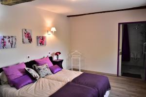 um quarto com uma cama grande e almofadas roxas em Mon Savoureux Jardin em Challain-la-Potherie