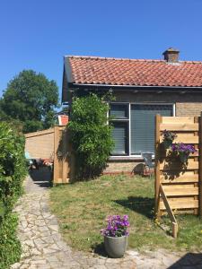 ein Haus mit einem Zaun und einem Blumentopf im Hof in der Unterkunft De Cel in Nes