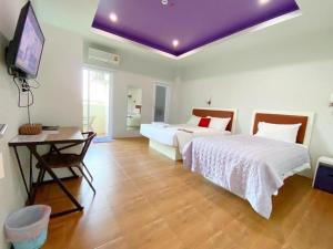 a bedroom with two beds and a purple ceiling at Namthip Residence in Trang