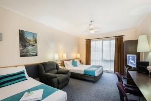 Habitación de hotel con 2 camas, sofá y silla en Australia Park Motel en Albury