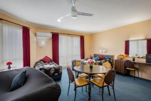 een woonkamer met een bank en een tafel met stoelen bij Australia Park Motel in Albury