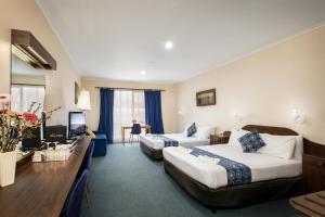 a hotel room with two beds and a desk at Australia Park Motel in Albury