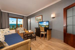 a living room with a couch and a desk with a television at Hotel IPV Palace & Spa - Adults Recommended in Fuengirola