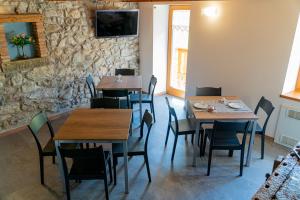 a restaurant with wooden tables and chairs and a stone wall at B&B Da Pieri in San Giovanni Bianco