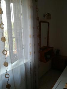 uma casa de banho com um espelho, uma cortina e uma janela em Machi's Guest House em Mithimna