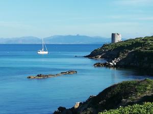 a boat in a body of water with a lighthouse at Casa San Salvatore in Càbras +15 photos