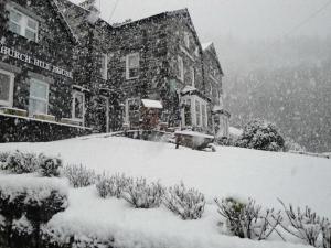 un bâtiment avec une pile de neige devant lui dans l'établissement Church Hill House, à Betws-y-coed