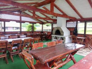 Habitación con mesas y sillas de madera y chimenea. en Pensiunea Iozefina, en Moieciu de Jos