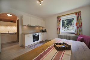 a living room with a table and a kitchen at Gästehaus Lienharterhof in Obertilliach