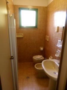 La salle de bains est pourvue de toilettes, d'un lavabo et d'une fenêtre. dans l'établissement Hotel Valentino, à Pinarella
