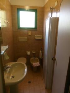a bathroom with a sink and a toilet and a window at Hotel Valentino in Pinarella