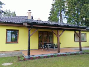 uma casa amarela com cadeiras e mesas num quintal em Sunny House em Lipno nad Vltavou