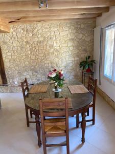 a dining room table with chairs and a stone wall at Gîte de Lamothe-d’Alès in Lavergne +5 photos