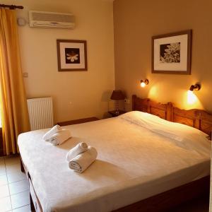 a bedroom with a bed with two rolled towels on it at Pegasus Hotel & Coastal Cafe in Kala Nera