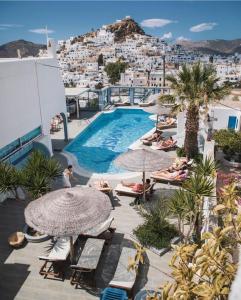 a pool on the roof of a hotel with people laying on the chairs at Sunrise Hotel in Ios Chora