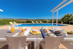een tafel met eten naast een zwembad bij Casa das Pedrinhas By ALzira in Algoz