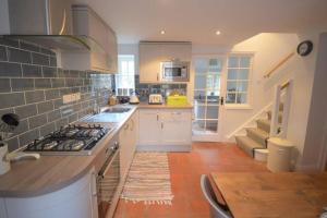a kitchen with white cabinets and a stove top oven at Brook Cottage - Luxury in Mundesley in Mundesley