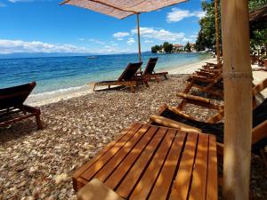 a beach with chairs and an umbrella and the ocean at Pegasus Hotel & Coastal Cafe in Kala Nera