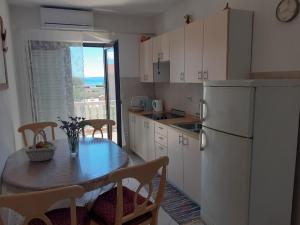 eine Küche mit einem Tisch und einem weißen Kühlschrank in der Unterkunft Apartments Lea & Eva in Privlaka