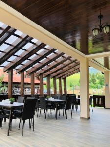 a patio with tables and chairs under a wooden ceiling at Pensiunea Maria in Colibiţa