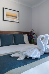 a bed with two swan towels on a blue rug at New Steine Hotel - B&B in Brighton & Hove