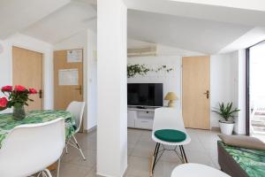 een woonkamer met een tafel en stoelen en een televisie bij Apartment & rooms Ivica in Krk