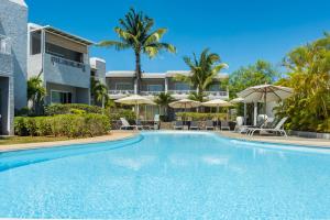 einem Pool vor einem Gebäude mit Sonnenschirmen in der Unterkunft Voile Bleue Boutique Hotel in Trou aux Biches