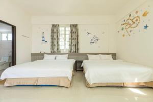 Dos camas en una habitación con paredes blancas. en 實在玩家民宿, en Magong