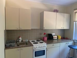 a kitchen with white cabinets and a stove and a sink at Apartment on Karja in Narva-Jõesuu