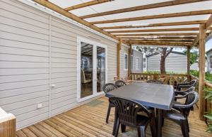 a patio with a table and chairs on a deck at Particulier loue ce mobil-home 3 chambres, tout confort in Valras-Plage