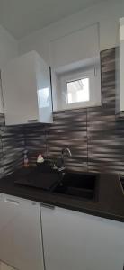 uma cozinha com um lavatório e uma janela na parede em Apartment Lukrecija em Selce