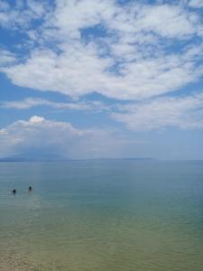 two people swimming in the water on a beach at Apartments Christina in Nea Vrasna