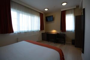 
a hotel room with a bed, desk and television at Hotel Taormina Brussels Airport in Zaventem
