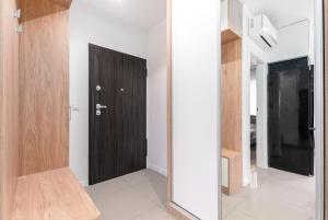 - un couloir avec une porte en bois et un miroir dans l'établissement BG Apartments Grzybowska, à Varsovie