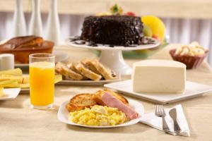 a table topped with plates of breakfast foods and orange juice at Hz Hotel in Patos de Minas
