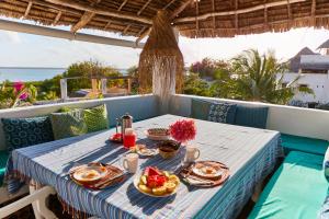 a table with plates of food on a balcony at Banana House and Wellness Centre in Lamu