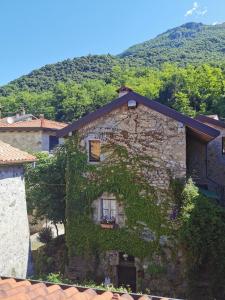 a building covered in ivy in front of a mountain at Alla Torre del Barbarossa B&B FORESTERIA in Mandello del Lario