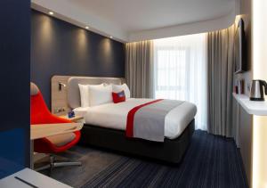 a hotel room with a bed and a red chair at Holiday Inn Express Edinburgh City Centre, an IHG Hotel in Edinburgh