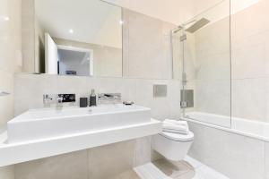 een witte badkamer met een wastafel en een toilet bij Bermondsey Central London Apartments in Londen