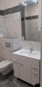 a white bathroom with a toilet and a sink at Hotel & Restauracja Glass in Radom