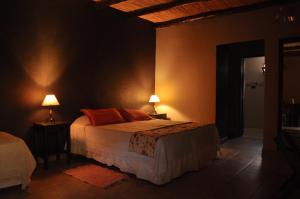 a bedroom with a bed and two lamps on two tables at Casagrande Hotel de Adobe in Tinogasta