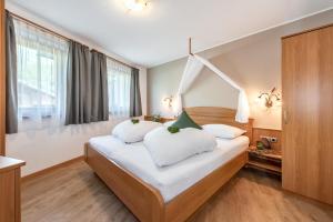 a bedroom with a large white bed with white pillows at AlpenChalet Niederkofler in San Giovanni in Val Aurina