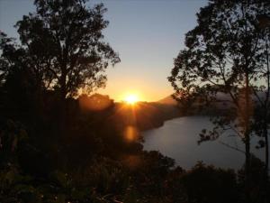a sunset over a river with trees in the foreground at Bukit Kembar Ecotourism in Gitgit