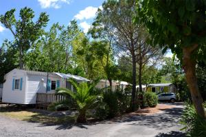 une caravane blanche avec une voiture garée dans une allée dans l'établissement Camping Les Salisses - Maeva, à Vias