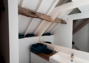 La salle de bains est pourvue d'un lavabo blanc et d'un plafond en bois. dans l'établissement Gîte de l'Étang, à Frasnes-lez-Anvaing