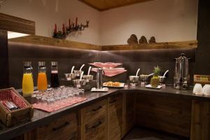 um buffet com bebidas e copos no balcão em Garni Hotel Wildanger em Zöblen
