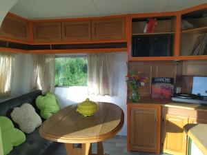 a living room with a table and a kitchen at cararetro , caravane chauffée et climatisée in Saint-Sylvain-Bellegarde